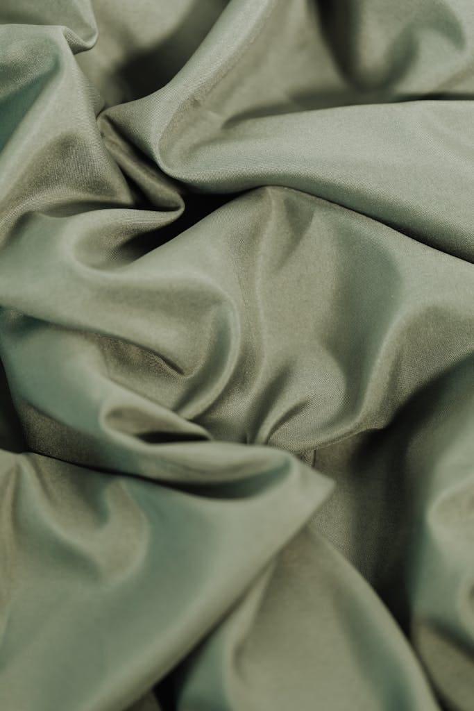 Close-up of rippled, pastel green fabric texture, ideal for textile backgrounds.